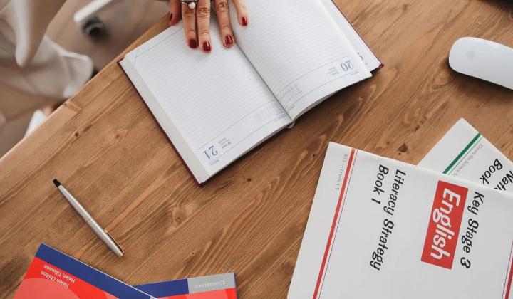 Sešit a učebnice angličtiny na dřevěném stole jako plán studia od nuly